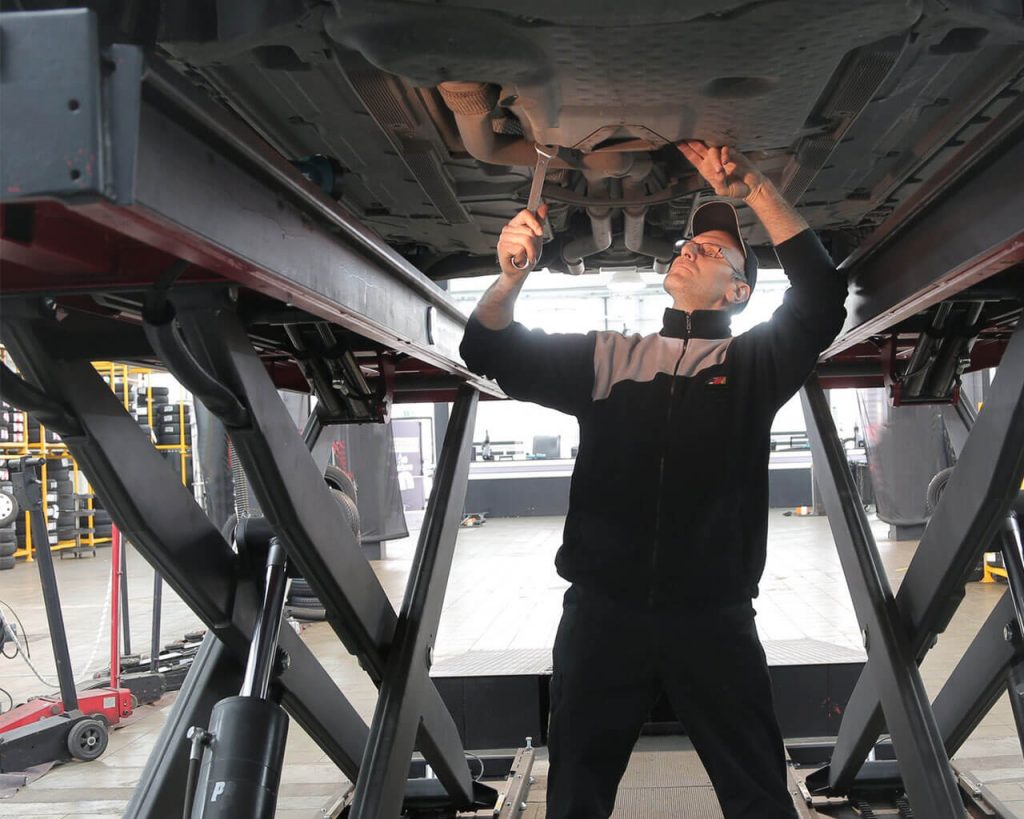 An automotive mechanic repairing a hoist car